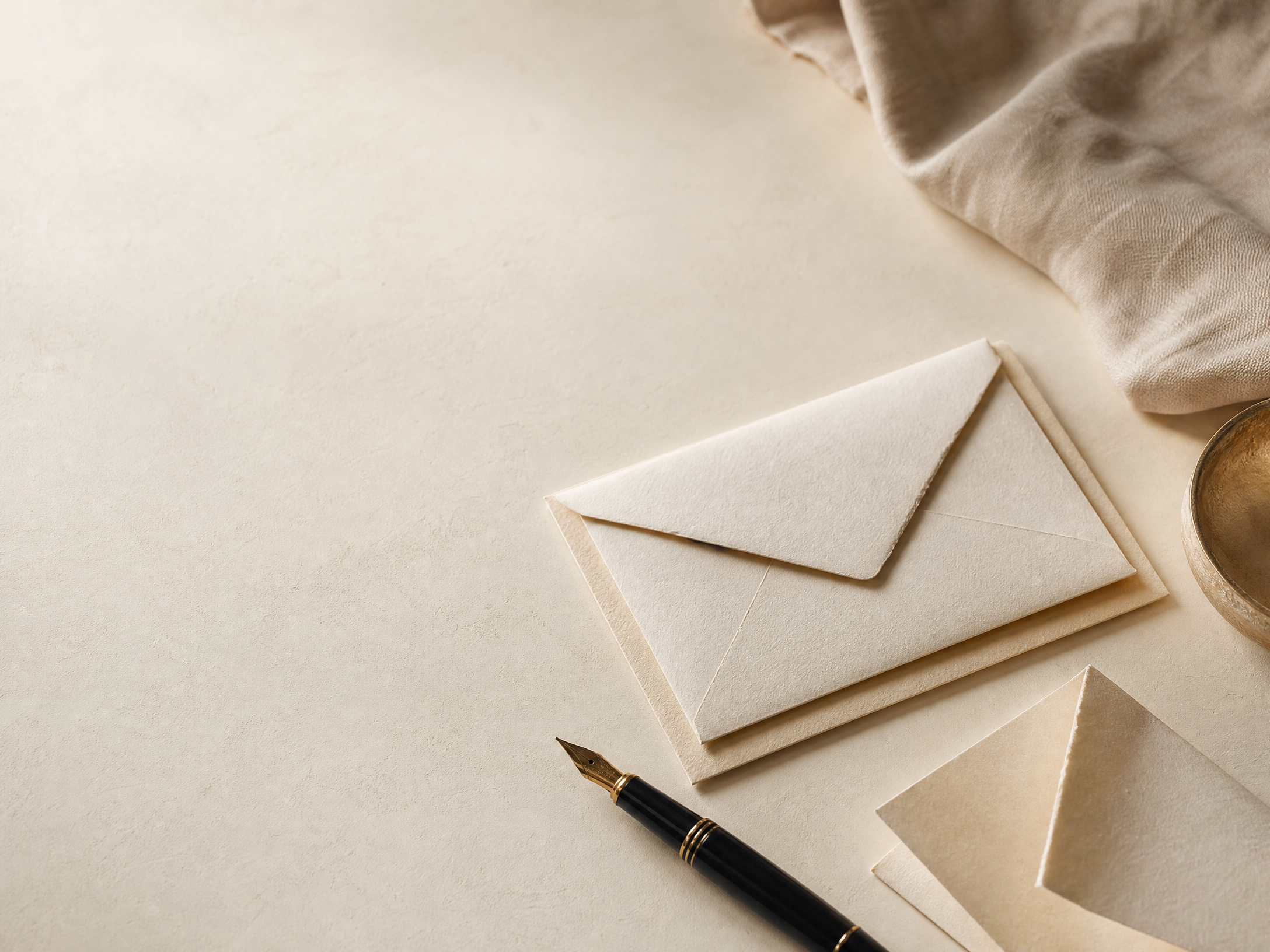 Paper envelopes and a pen arranged on an ivory desk